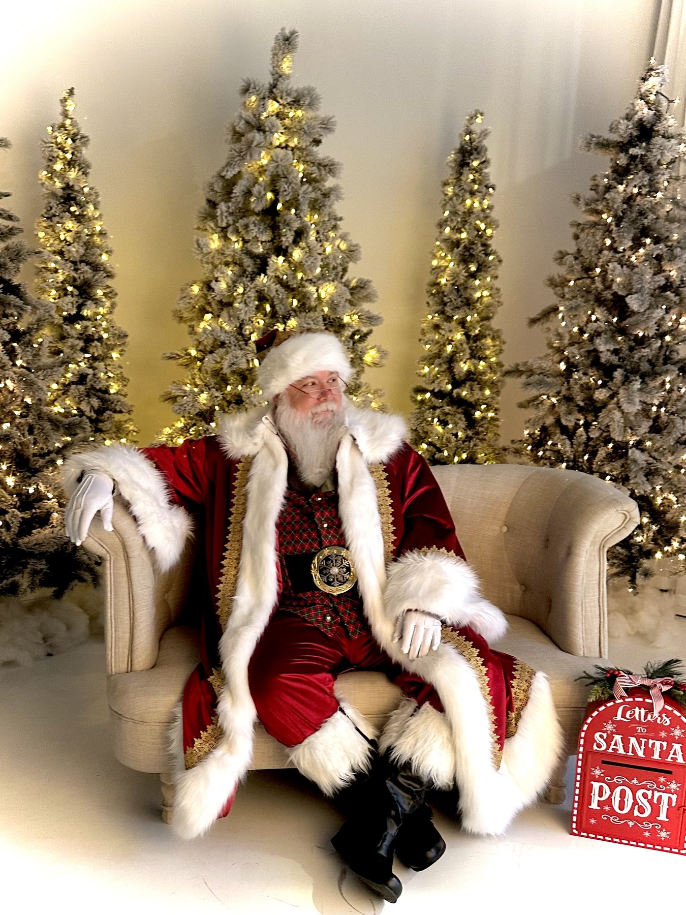 Gregg da Santa seated among lit Christmas trees